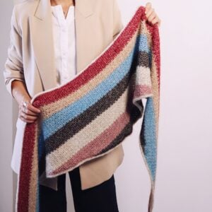 Mujer sosteniendo y mostrando la textura y caída del Chal ARIS de crochet versión Worsted multicolor, patrón de ShowroomCrochet.